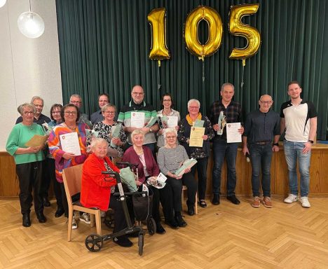Gruppenfoto von Mitgliedern des TuS Horn, die Auszeichnungen und Urkunden in den Händen halten. Sie stehen vor goldenen Zahlen der Zahl 105.